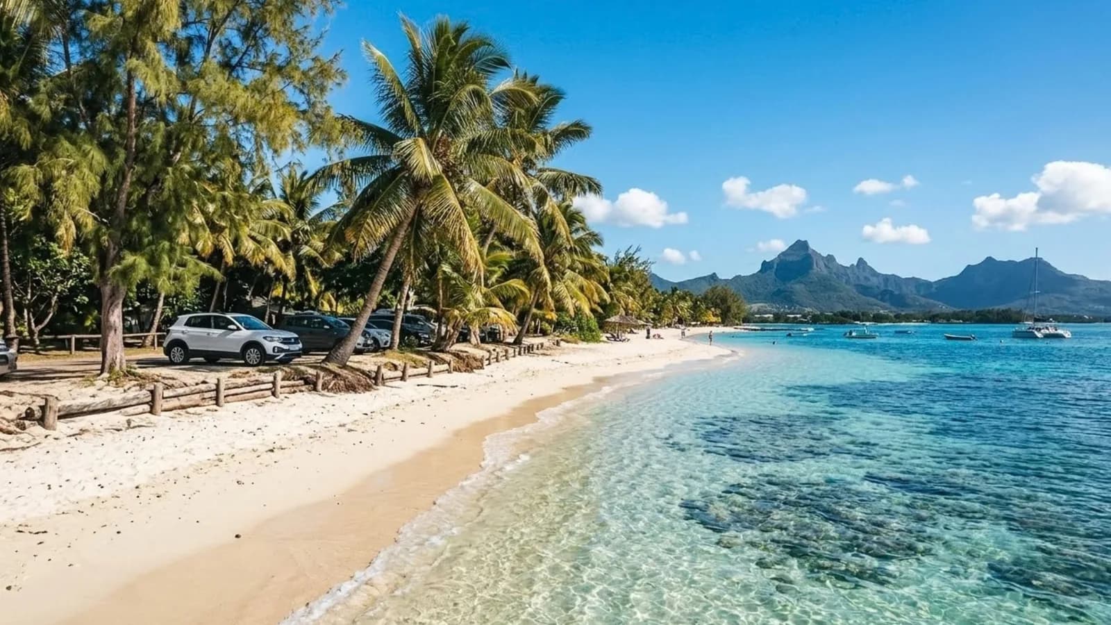 A white sand beach lined with palm trees and a calm turquoise lagoon, with a car parked nearby
